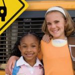 Three kids standing in front of a bus smiling