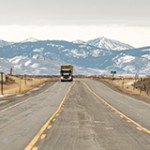 Image of a road in winter with a truck far off in the distance