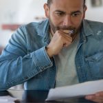 An image of man thinking and looking at a piece of paper