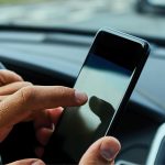 Image of a person using their phone while in the car