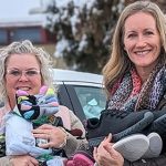 Four Idaho Power female employees holding socks, shoes and other donations