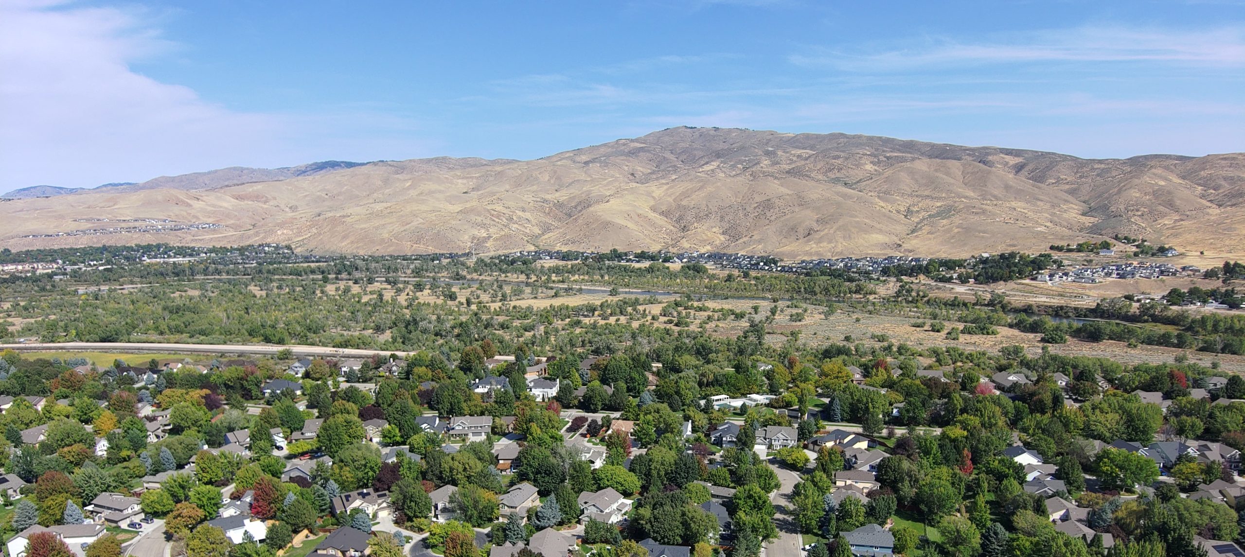 Image is an aerial view of a Boise, ID neighborhood with mountains in the background.