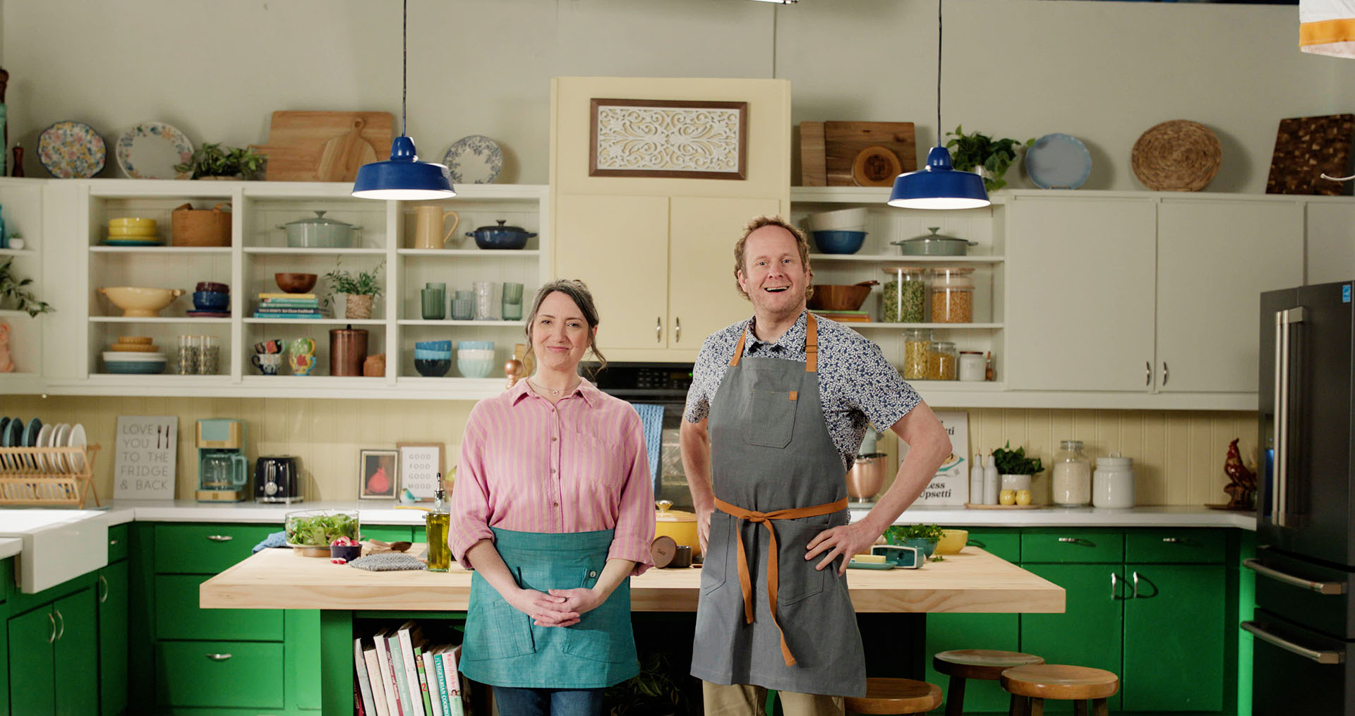 A man and woman standing in a kitchen, smiling