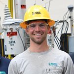 Three male Idaho Power employees wearing hard hats and smiling at the camera