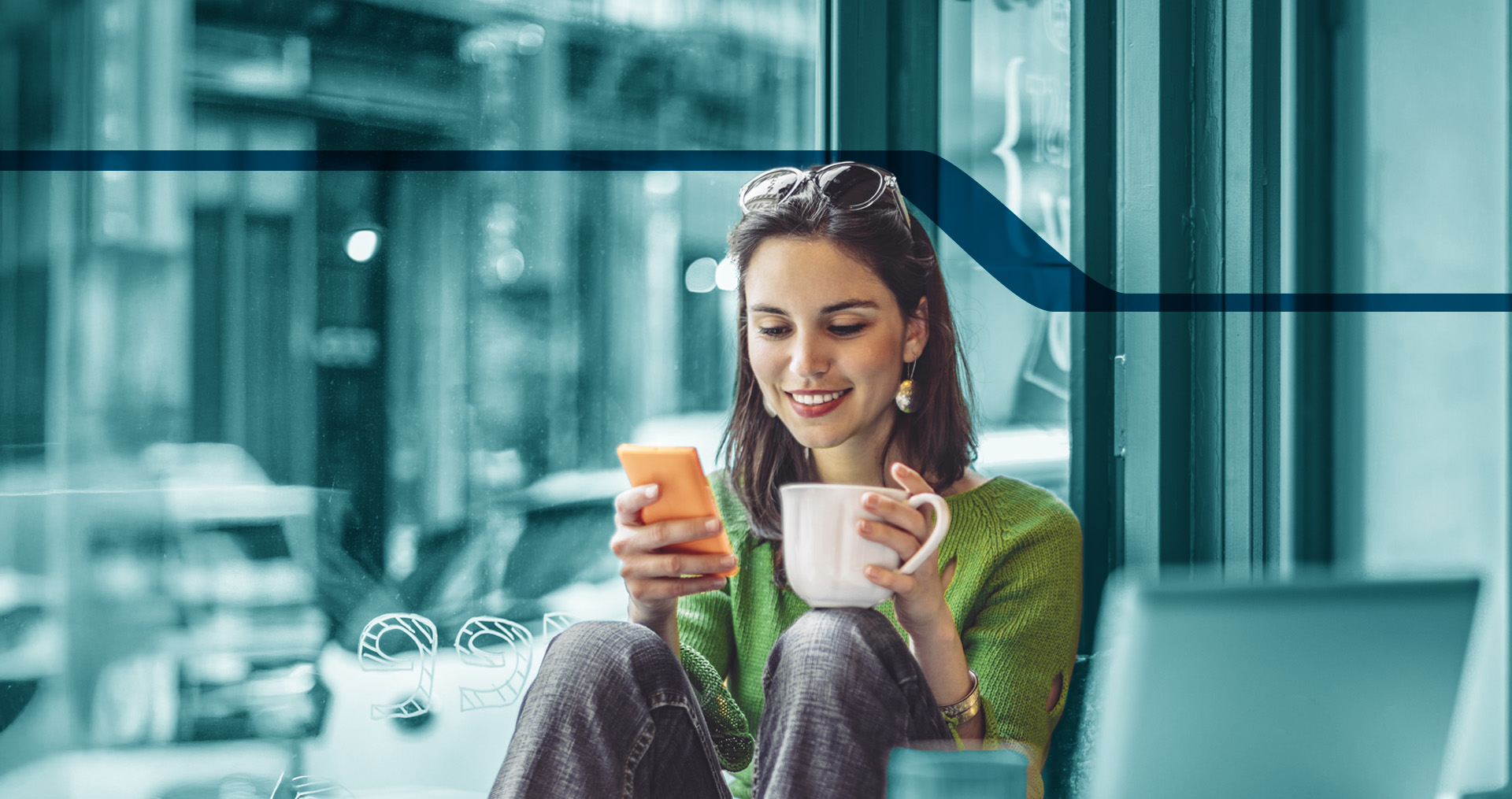 Image is of a woman holding a coffee cup and looking at a cell phone.