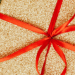 Gift-wrapped packages in holiday colors and a grey blanket alongside.